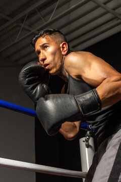 Low angle Hispanic boxer in powerful fighting stance inside boxing ring