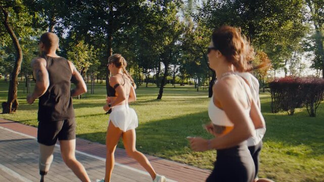 Fitness group resumes running together along sunny park path
