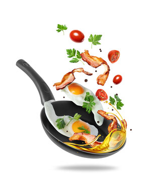 Fried eggs and fried bacon slices fly out of the frying pan, isolated on white background.