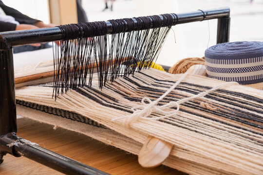 traditional sadu weaving on wooden loom uses minshaza tool to pack weft thread tightly. ancient weaving creates durable fabric and preserves emirati cultural heritage craft today.