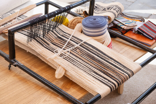 traditional sadu weaving on wooden loom with natural wool thread and wooden shuttle tool. bedouin weaving creates durable fabric. ancient weaving preserves emirati cultural heritage.