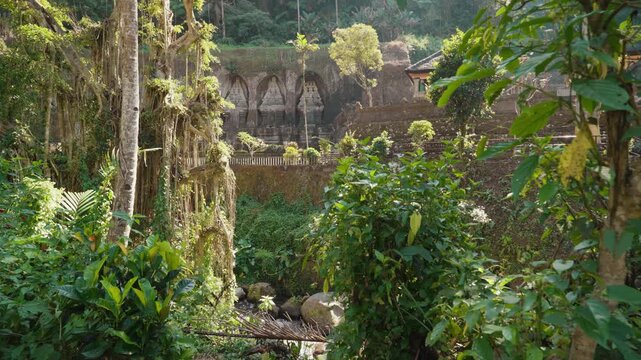 Ancient stone shrines and rock carvings at Gunung Kawi Temple surrounded by lush tropical vegetation in Tampaksiring Bali Indonesia