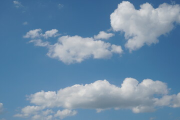 Fototapeta premium White fluffy clouds in the sky. Blue sky and cloud cover on a sunny summer day. Empty background, copy space