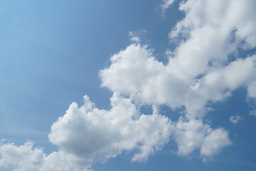 Fototapeta premium White fluffy clouds in the sky. Blue sky and cloud cover on a sunny summer day. Empty background, copy space