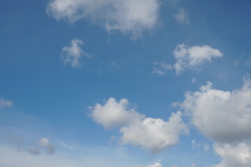 Fototapeta premium White fluffy clouds in the sky. Blue sky and cloud cover on a sunny summer day. Empty background, copy space