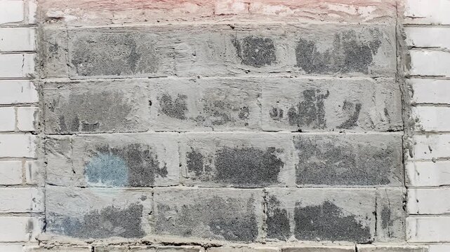 Seamless 4K looping vertical movement across an old brick wall with repaired white masonry section. Ideal for construction backgrounds and architectural visuals.