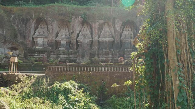 Ancient stone shrines and rock carvings at Gunung Kawi Temple surrounded by lush tropical vegetation in Tampaksiring Bali Indonesia