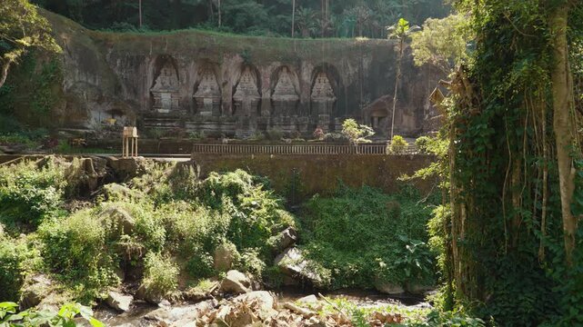 Ancient stone shrines and rock carvings at Gunung Kawi Temple surrounded by lush tropical vegetation in Tampaksiring Bali Indonesia