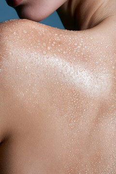 Water droplets glisten on wet shoulder skin macro