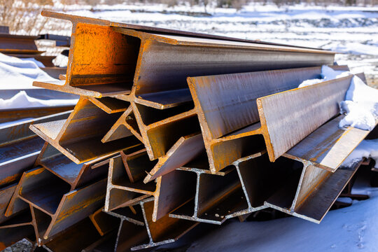 Weathered Steel I-Beams Stacked Outdoors in Snow