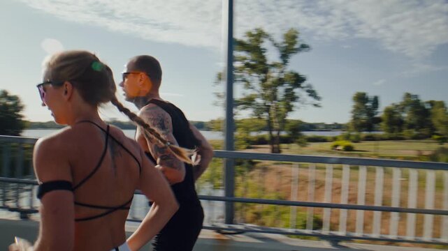 Group of runners jogs side by side along sunny riverside pathway
