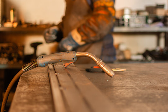 Close up of welding torch on workbench with welder in background