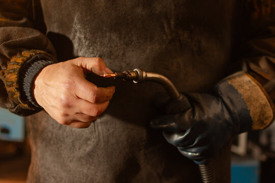 Close up of worker adjusting welding torch with bare hand