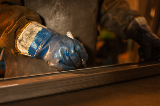 Close up of gloved hand marking metal piece with marker