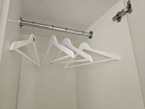Four white hangers on a metal rod inside