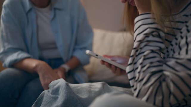Teenage girl absorbed in smartphone whil mother tries to talk and take  device away, illustrating phone addiction, excessive screen time, digital dependency and parenting struggles