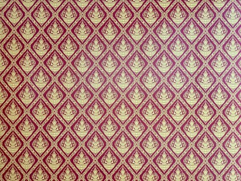Traditional "Thai Kanok" Pattern with Ornate Golden Deity Motifs on Red Background.