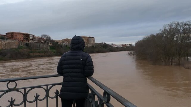 Woman watching flooded duero river in tordesillas