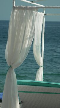 Beach, ocean, cabana, white curtains waving by tranquil sea, tropical relaxation, tranquil summer vacation. Vertical video