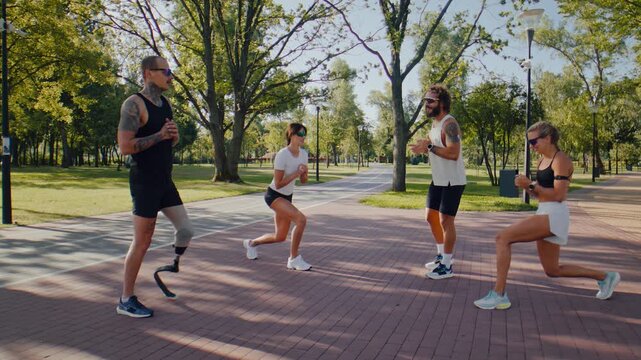 Fitness group performs walking lunges during park warmup