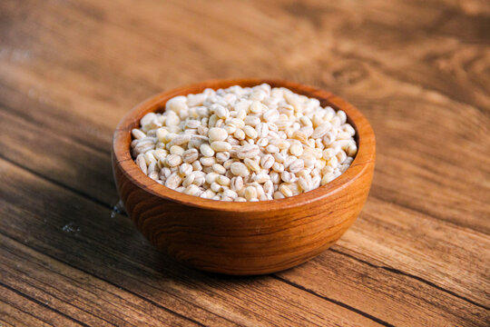 Pearl barley in wooden bowl on wooden table