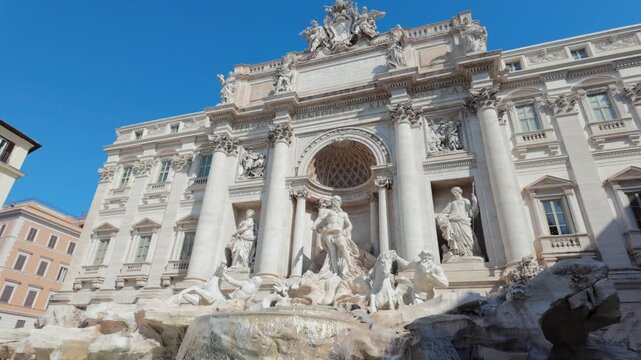 Low angle view of the iconic Trevi Fountain against a clear blue sky in Rome, Italy