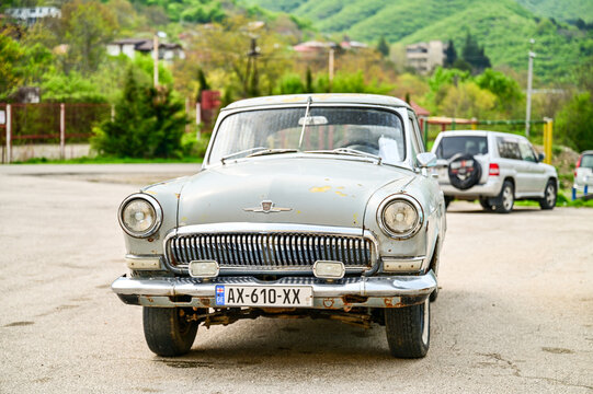 Gray historic GAZ-21 Volga classic car from the 1950s, in a parking lot in front of green hills near Shignaghi; Soviet classic cars, Georgia