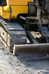 Close up of yellow excavator continuous track and front dozer blade on construction site ground © Светлана Кушнир