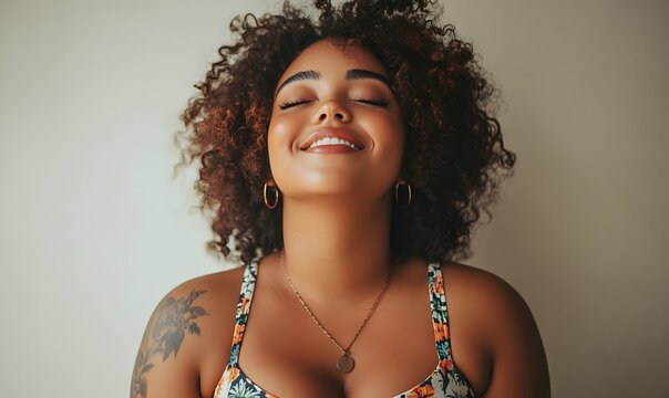 Smiling young woman with dark curly hair and closed eyes expressing joy and inner peace