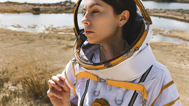 Close up portrait of a woman astronaut holding a dry blade of grass in her hand