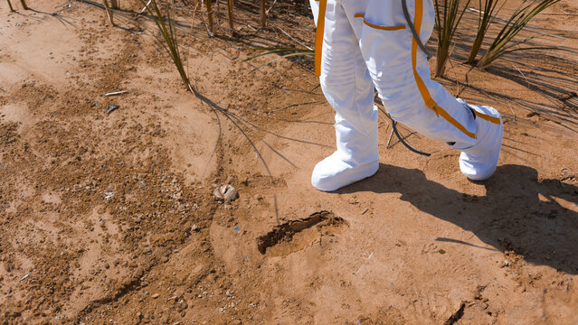 White boots of a spacesuit and a fresh footprint left on red planet sand