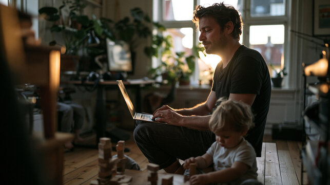 Father Working on Laptop at Home Near Playing Toddler