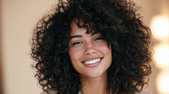 Portrait of a smiling African American woman with natural curly afro against a warm beige background