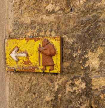 Gelbes Keramikschild mit der Aufschrift Via Francigena und einem Plger mit Stab, typische Wegmarkierung eines historischen Pilgerweg von Canterbury nach Rom, San Quiricio, Toskana, Italien