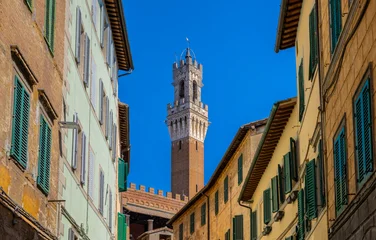 Blick durch eine enge Gasse auf den Torre del Mangia, den markanten Glockenturm des Palazzo Pubblico in Siena, Toskana, Italien © spuno