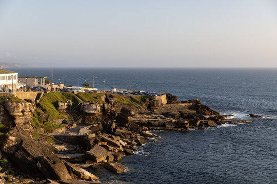 golden hour sunset wide shot of Ericeira coast in Portugal with cliffs, ocean, and buildings