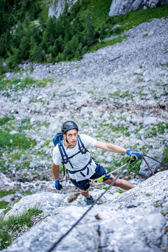 Climber ascending the Seeben via ferrata near Seebensee in Tyrol, Austria, secured to a steel cable on a steep limestone rock face, alpine adventure, mountaineering and outdoor climbing