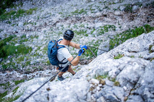 Climber ascending the Seeben via ferrata near Seebensee in Tyrol, Austria, secured to a steel cable on a steep limestone rock face, alpine adventure, mountaineering and outdoor climbing