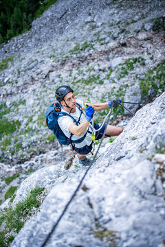 Climber ascending the Seeben via ferrata near Seebensee in Tyrol, Austria, secured to a steel cable on a steep limestone rock face, alpine adventure, mountaineering and outdoor climbing