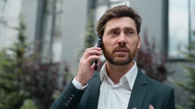 Serious sad middle-aged Caucasian business man talking mobile phone in city. Mature businessman male professional manager executive talk smartphone call communicating about work with telephone outdoor