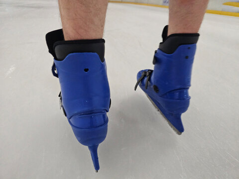 Skater practicing on ice with blue skates during afternoon