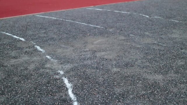 Shot put metal ball landing on gravel sector on a track and field stadium, close up video.