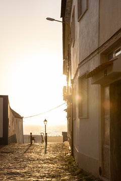 view from narrow residential cobblestone street in Ericeira, Portugal looking towards ocean during golden hour