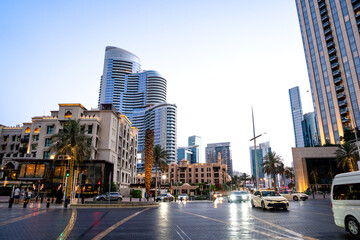 Obraz premium At sunset, a busy city with skyscrapers, cars, and people