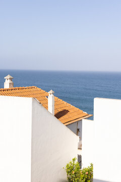 white architectural house by the sea with orange tiled roof with blue ocean in the background, minimal, negative space