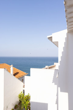 white architectural house by the sea with orange tiled roof with blue ocean in the background, minimal, negative space