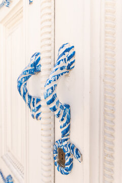 traditional white building with closeup of door handle painted in nautical rope style