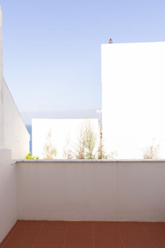 empty orange tiled patio in a white coastal architectural home with ocean in the background