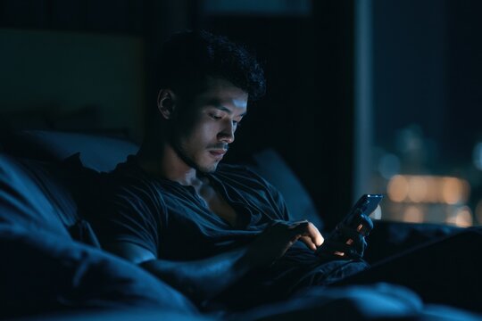 Intimate conversation in dim lighting: solitary man texting in a quiet room