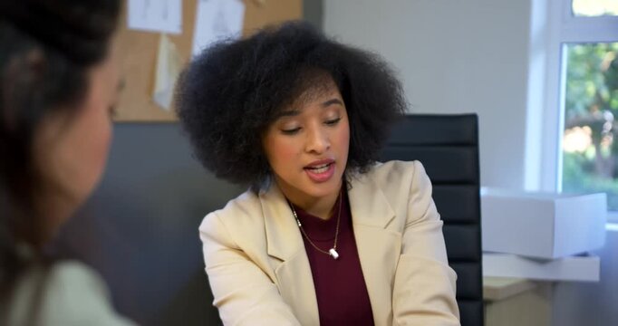 Seeing desk files, African American woman in beige blazer gesturing, explaining plan to Asian woman